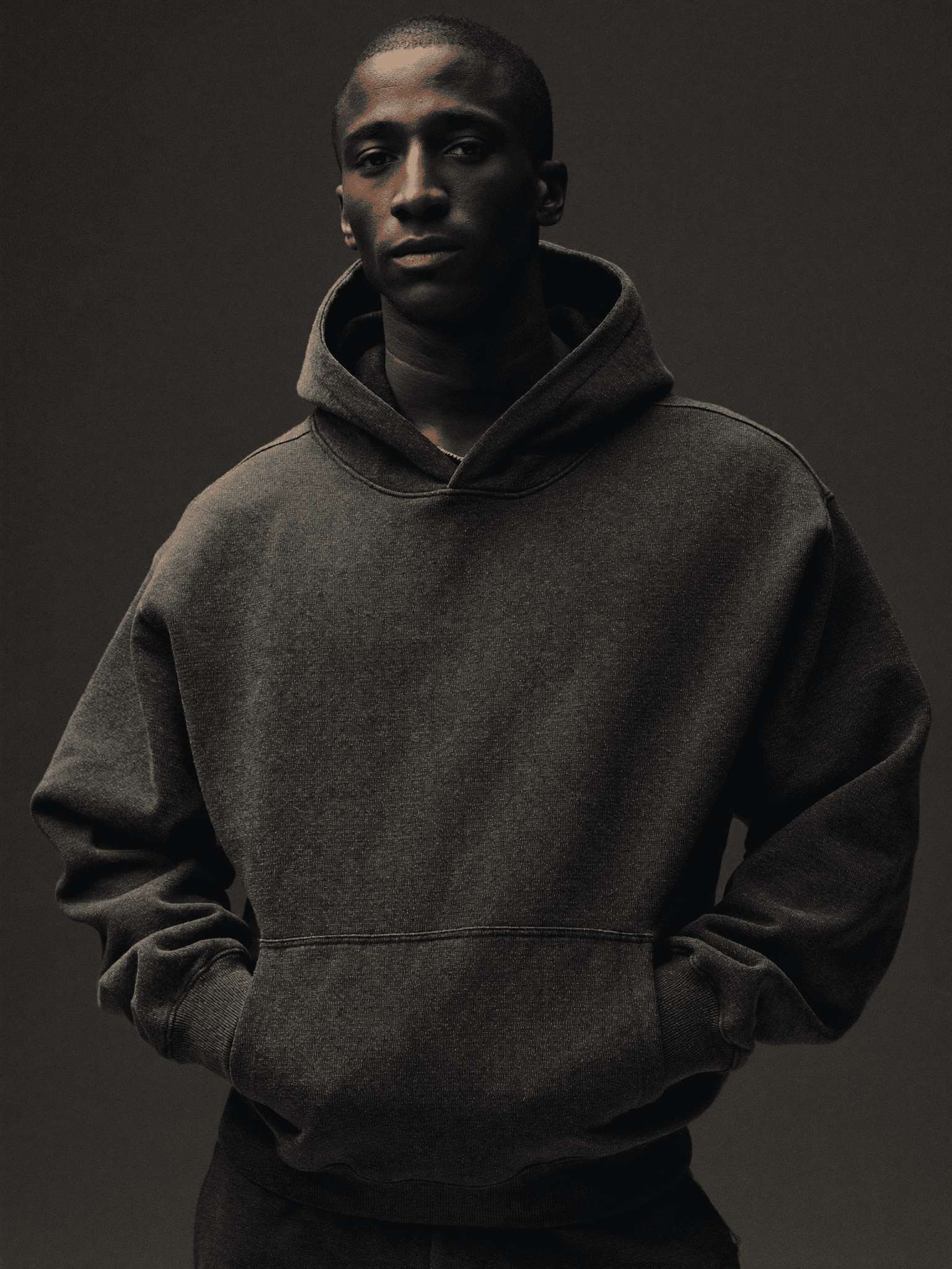 A man in the charcoal Founding Hoodie, shot in low light.